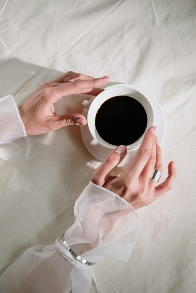 hands with silver jewellery hold a cup of coffee